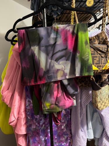 Customer's Naked Print Stirrup Leggings with a colorful floral pattern hanging on a closet rack.