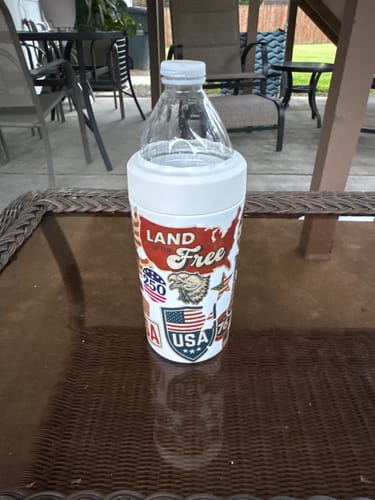 Customer's white Universal Buddy can cooler with patriotic graphics, holding a plastic water bottle on a patio table.