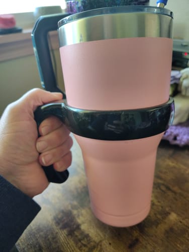 Reviewer's hand holding a sturdy black handle attached to a pink tumbler cup.