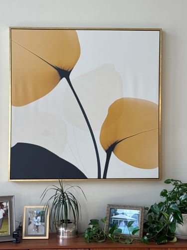 Customer's Golden Leaves canvas art with yellow and black abstract leaf design, mounted on a living room wall.
