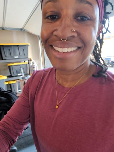 Customer's Ellie Initial Love Lock 18k Gold Necklace worn around neck, showing the gold lock pendant.