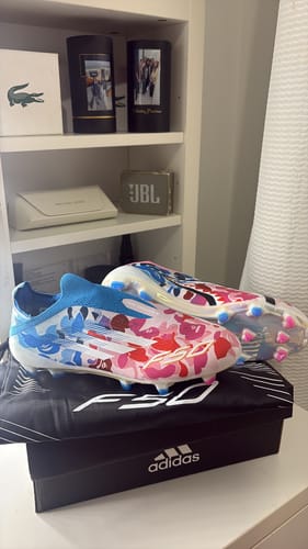 Customer's F50 x Bape Laceless FG football boots with colorful graphic patterns, resting on their packaging and bag.
