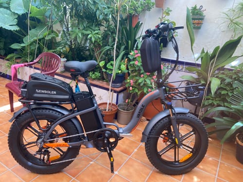 Customer's Vakole Y20 Pro fat bike parked in a patio garden setting, showing front basket, rear rack, and black tires.