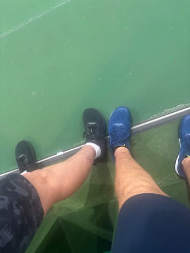 Customer's CUURT Muuv court shoes in blue and black, worn by reviewer on a pickleball court.