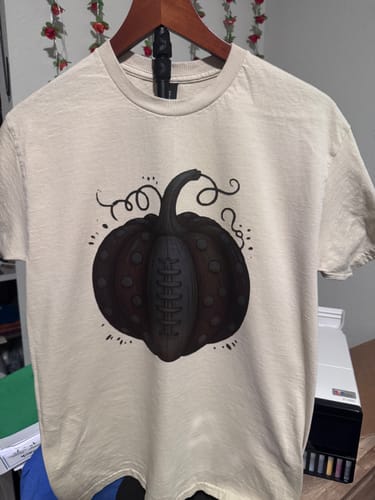 Customer's cream-colored shirt printed with a dark pumpkin-shaped football graphic.