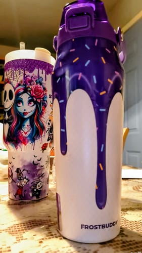 Customer's purple Bottle Buddy 24oz next to a character-themed tumbler on a textured surface.