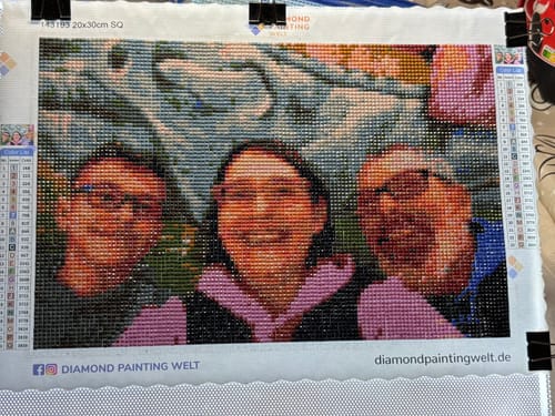 Kunden Diamond Painting mit einem persönlichen Foto von drei lächelnden Personen, vollständig mit bunten Steinchen besetzt.