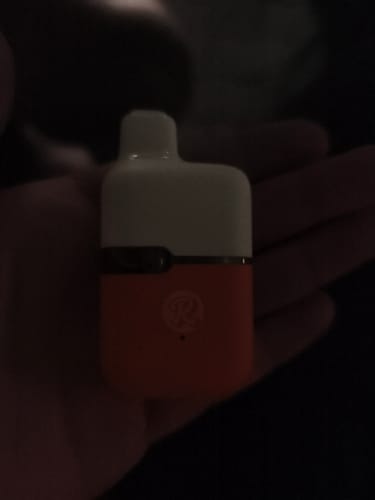 Customer's compact THC-A Vape device held in a hand, showing the white and orange dual-tone design.