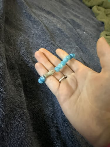 Customer's blue beaded Voyage Bracelet held in a hand