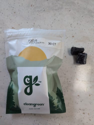 Customer's Focus Gummies bag and two dark, sugar-coated gummy chews on a speckled counter.