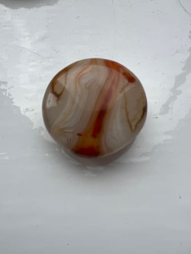 Customer's polished round crystal from the VIP Crystal Club with swirling tan, white, and red patterns.