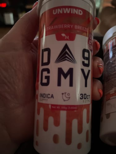 Reviewer's hand holding a cylindrical container of Delta 9 Strawberry Breeze gummies.