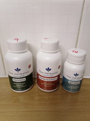 Customer's Reset Bundle of three white bottles labeled The Herbalist, Moringa, Ashwagandha, and Sea Moss on a counter.