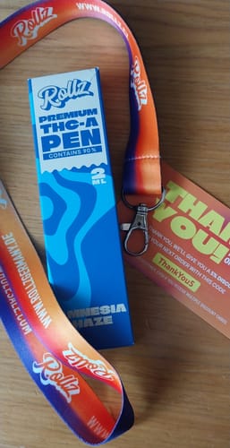Customer's Rollz THC-A Vape pen box with a branded orange lanyard and a thank you card on a wooden surface.