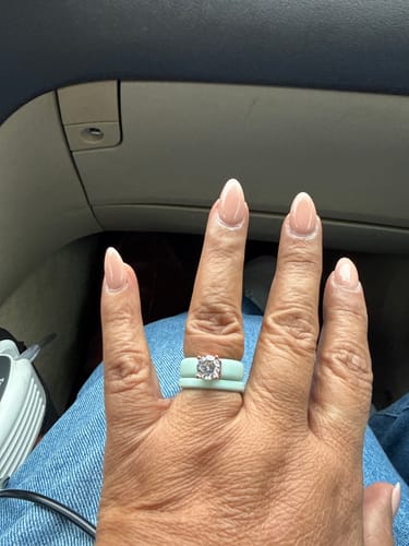 Customer's stackable light green silicone rings worn as a set on a hand.