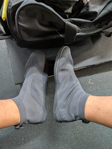 Customer's feet wearing the dark grey Otishi 2.0 Amaru Black knit sneakers in a gym setting.