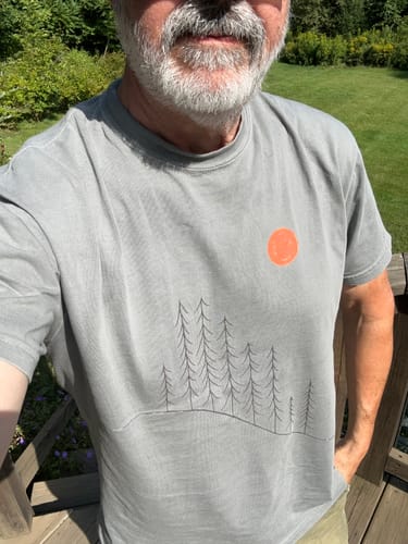 Customer's gray Sunrise Pines T-shirt featuring a line-art forest design and a small orange circle logo.