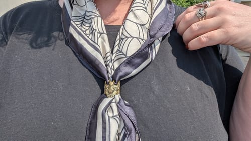 Customer's Bat Bandana Ring in solid brass, worn on a silky patterned scarf around a person's neck.