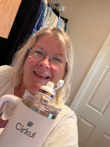 Customer smiling and holding a light-colored Cirkul water bottle with a cartridge attached.