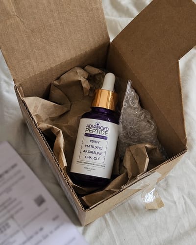 Customer's Advanced Peptide serum bottle in an open delivery box protected by paper and bubble wrap.
