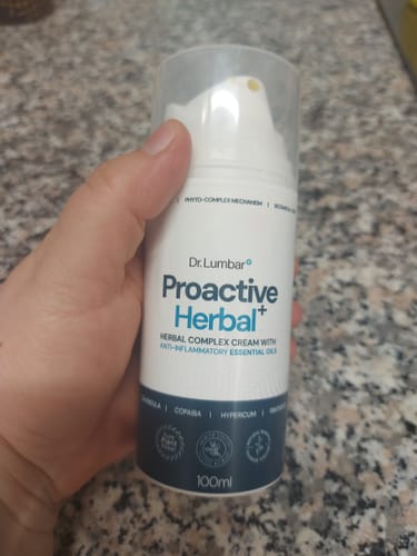 Reviewer's hand holding a 100ml bottle of Proactive Herbal+ cream with a clear cap.
