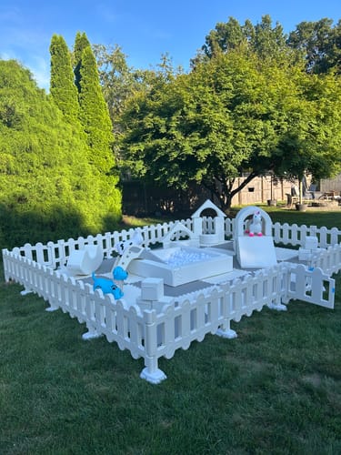 Customer's Soft Play plastic fence playpen set up outdoors on a grassy lawn with colorful foam shapes and a ball pit