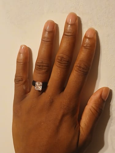 Customer's hand wearing a black silicone ring with a sparkling emerald-cut stone.