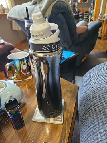Customer's FitSip water bottle with a labeled flavor cartridge, sitting on a wooden table near other items.