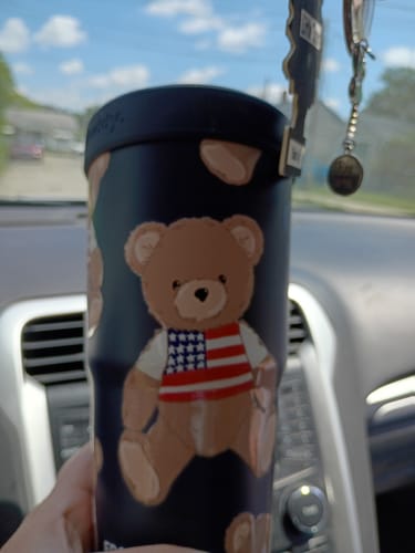 Customer's Mystery To-Go Buddy tumbler with a teddy bear pattern featuring an American flag shirt held in a car.
