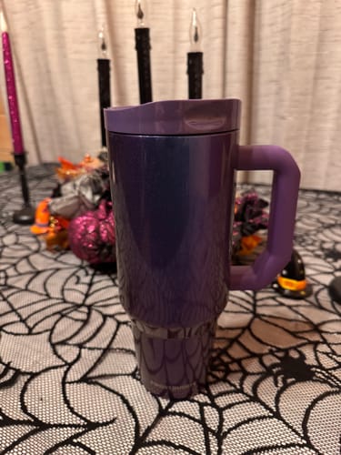 Customer's sparkling purple Thicc Buddy 40oz mug with a handle, set on a spiderweb tablecloth with Halloween decor.