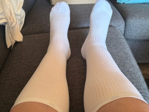 Anmelders hvide Diasocks støttestrømper båret på benene, mens de sidder i en sofa.