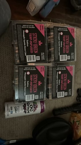 Customer's four boxes of Sticky Green pre-rolls and a grape flavored product on a surface