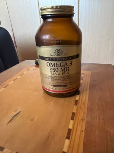 صورة من المراجع لزجاجة مكملات Solgar Triple Strength Omega-3 ذات اللون البني على طاولة خشبية