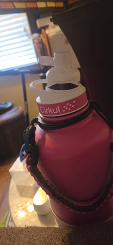 Customer's pink Cirkul bottle with a black carry strap, close-up.