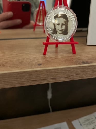 Customer's AtomStack laser engraving of a child's portrait on a round metal disc, set on a red mini easel.