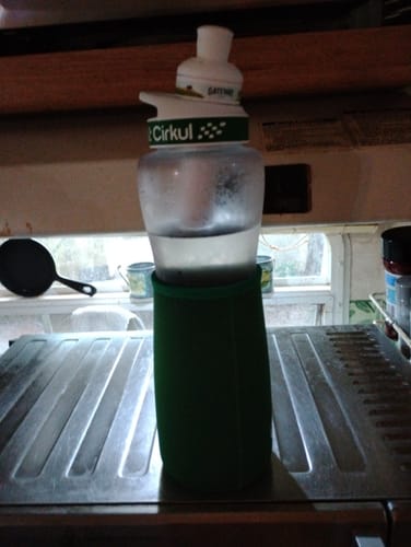 Customer's Cirkul bottle with a green sleeve sitting on a metal stove top.