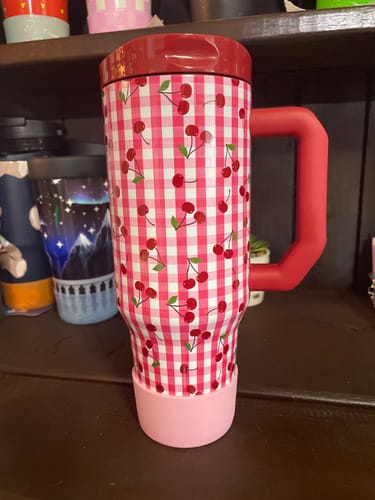 Customer's Cherry Gingham Thicc Buddy mug with a red handle and pink base sitting on a shelf.