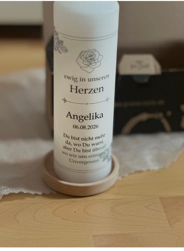 Kundenfoto der Trauerkerze Vintage Rosen mit personalisiertem Druck auf einem hölzernen Untersetzer.