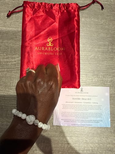 Reviewer's white marble howlite bead bracelet from the VIP Crystal Club, shown with a red gift bag and information card.