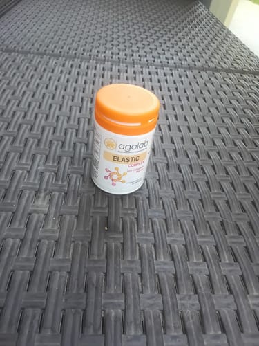 Customer's Collagene Elastic Complex bottle with an orange cap on a woven outdoor surface.