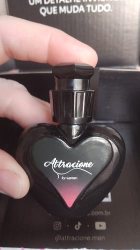 Customer's hand holding the black heart-shaped Perfume Attracione Sensual bottle in its packaging.