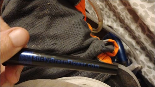 Customer's hand holding a black pre-roll joint with a website label, close-up.
