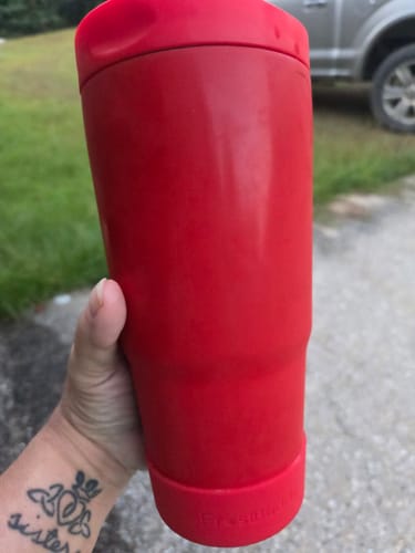 Customer's hand holding the bright red To-Go Buddy tumbler outdoors.