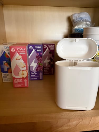 Customer's Cirkul cartridges and an empty white water bottle container sitting on a wooden shelf.