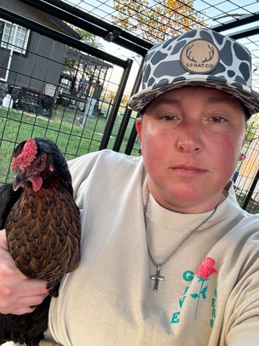 Customer's Hat of the Month Crew cap with patterned fabric and branded leather patch, worn while holding a chicken.