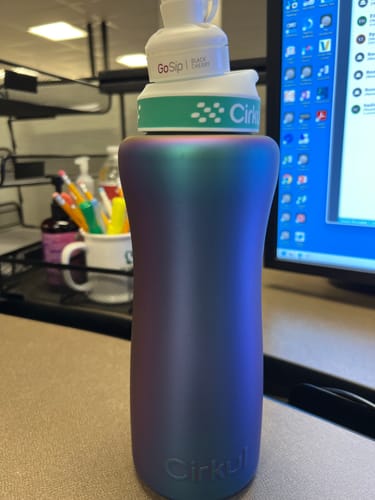 Customer's iridescent GoSip Black Cherry water bottle with Cirkul lid sitting on an office desk.
