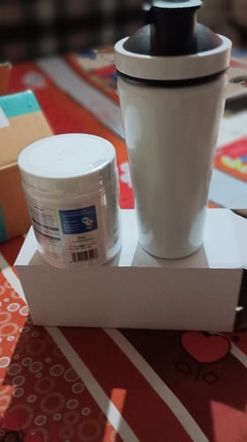 Customer's Wellcore Creatine Monohydrate tub and sleek stainless steel shaker standing together on a white box surface.