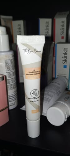 Customer's Advance Lip Pigmentation Cream tube standing upright among other skincare products on a dark surface.