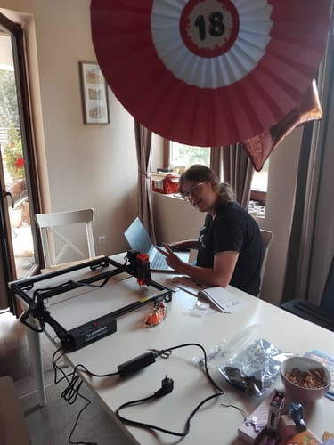 Customer's AtomStack A10 Pro V2 laser engraver set up on a white table with a person using a laptop nearby.