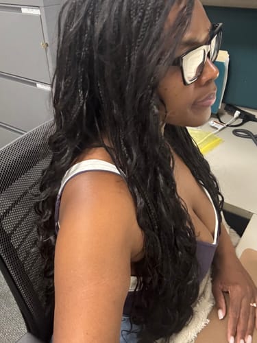 Customer's long black loose wave bulk hair extensions integrated into knotless boho braids, viewed from the side.